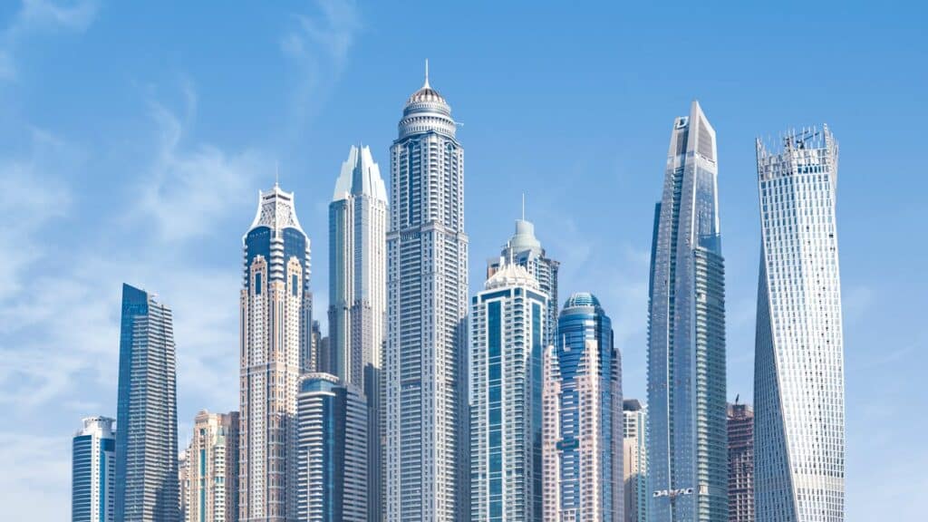Dubai Marina skyline with modern glass towers and the twisted Cayan Tower under a clear blue sky
