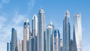 Dubai Marina skyline with modern glass towers and the twisted Cayan Tower under a clear blue sky