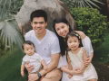Happy parents sitting outdoors with two young children