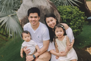 Happy parents sitting outdoors with two young children
